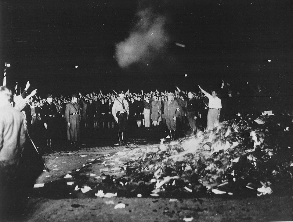 A bonfire of books on Berlin's Opernplatz at night, with SA members and the crowd giving the Nazi salute