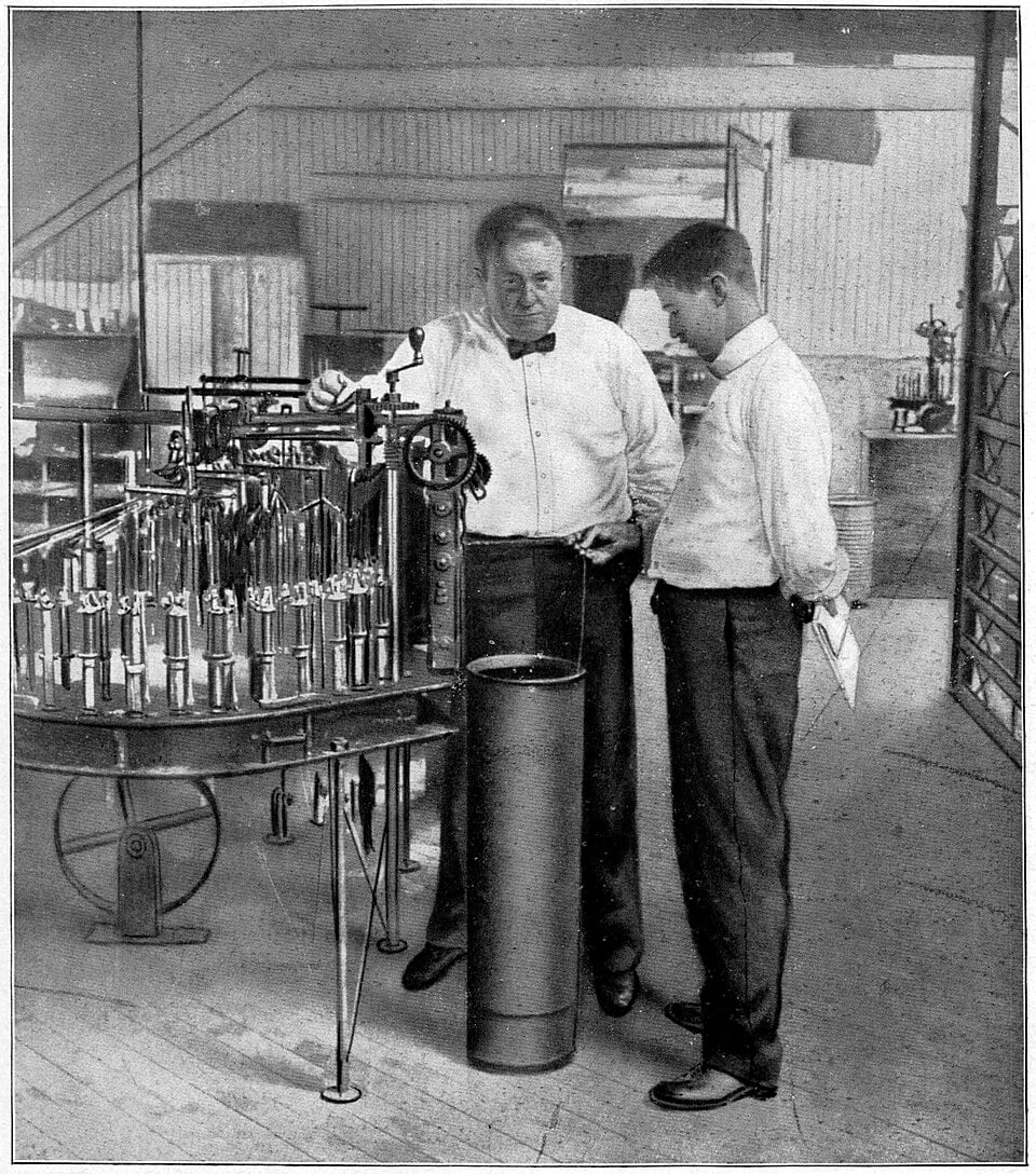 Frank Gilbreth, in a bow tie, standing beside a young operator at a textile machine
